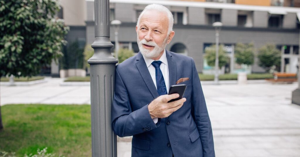 スーツ姿でスマホをいじる60代男性