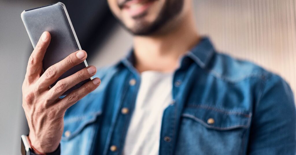 スマホを持って微笑む男性