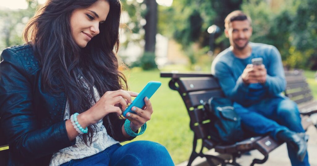 スマホを持ちながら隣の女性を見つめる男性