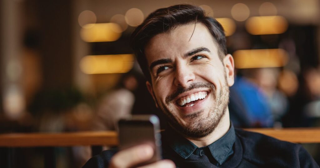 スマホを持って笑っている男性