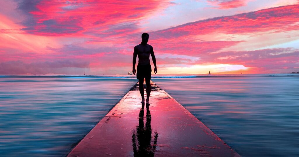 幻想的な夕日の海辺に佇む男性
