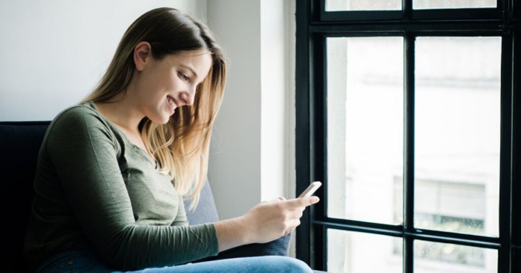 笑顔でスマホをチェックする女性