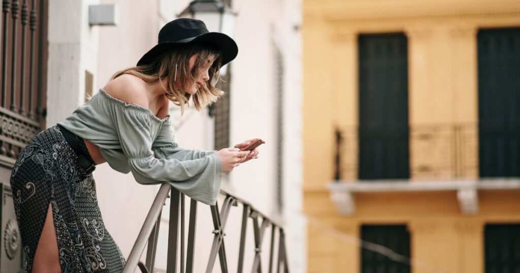 階段の踊り場でスマホを操作する女性