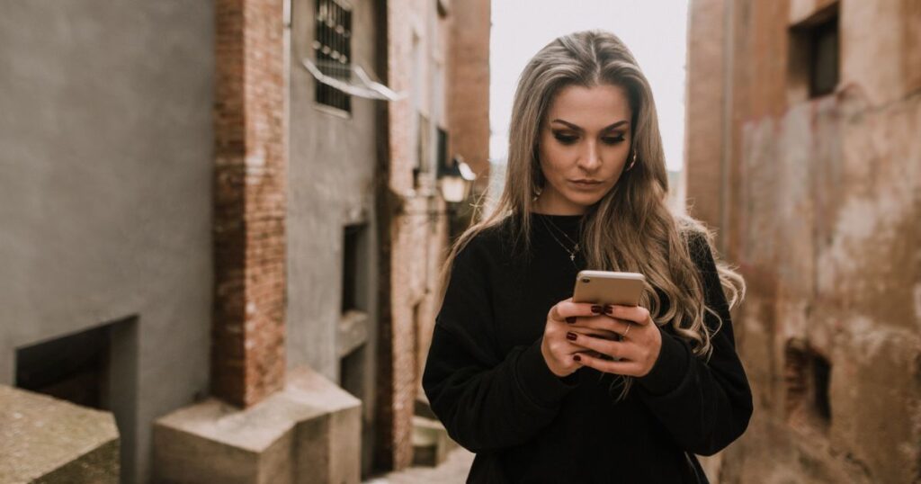路地で真剣な表情でスマホを操作する女性