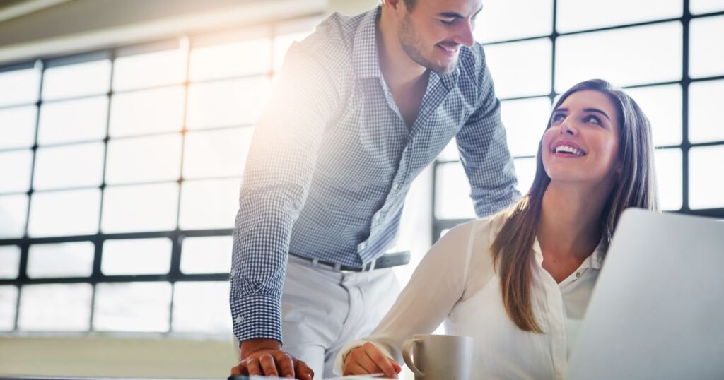 パソコンを触る女性に話しかける営業マン