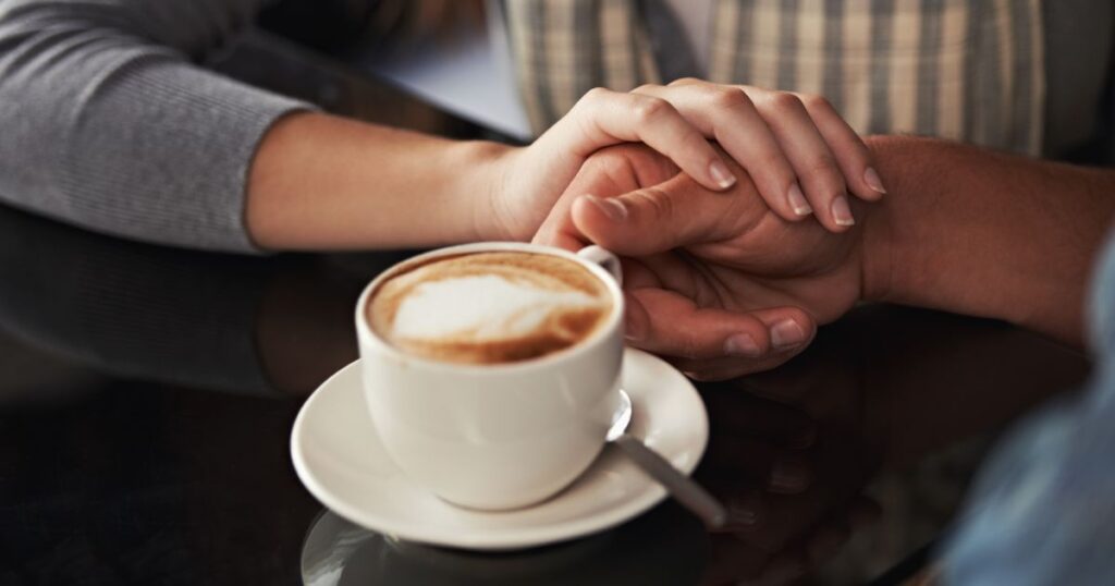 カフェで男性の手を握る女性