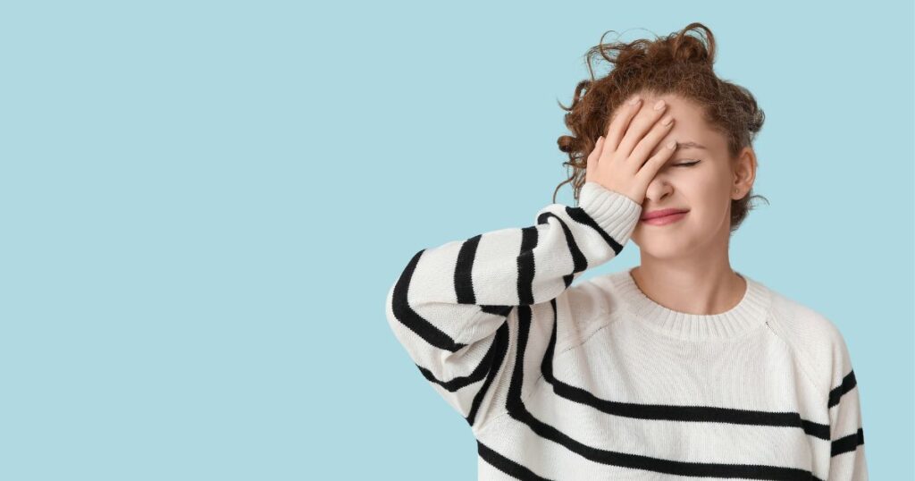 手で顔を押さえ気まずそうな表情の女性