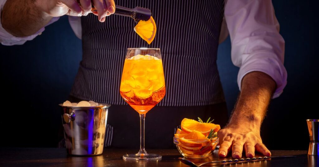 オレンジのお酒を作るバーテンダーの男性