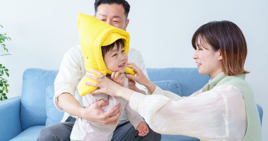 子供に防災頭巾を被せる女性と夫