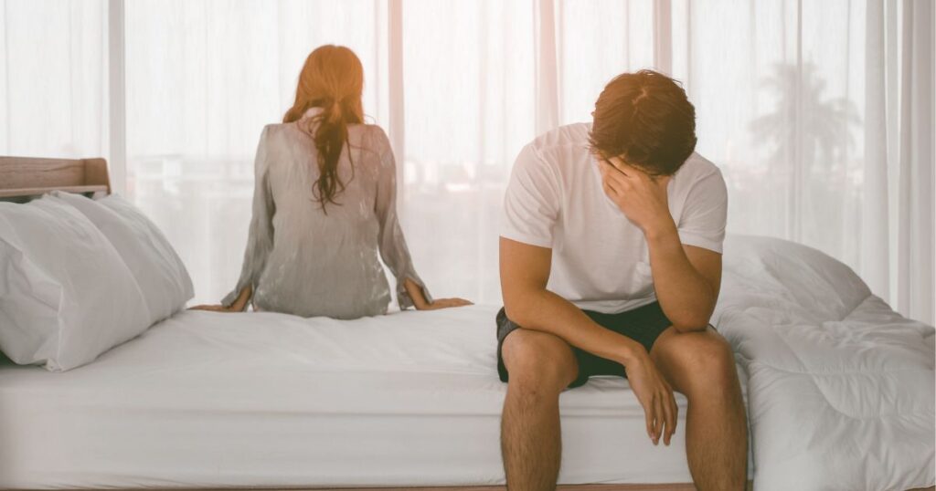 ベッドの端にそれぞれ背を向けて座る男女