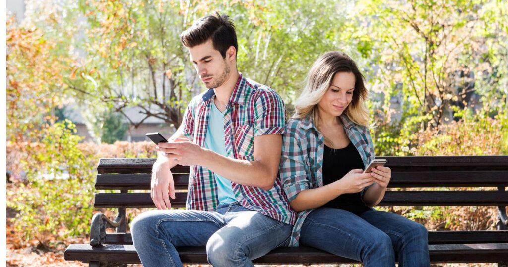 ベンチに腰掛けスマホをいじる男女