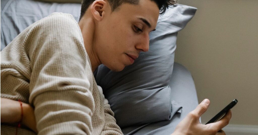 ベッドの中でスマホをいじる男性