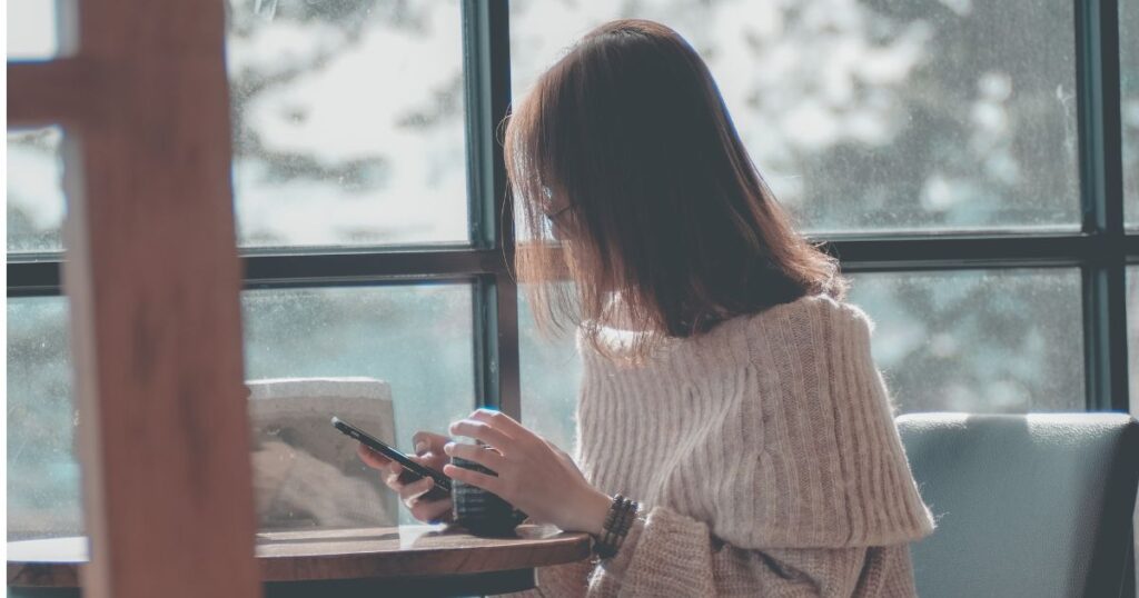ドリンクを飲みながら通知をチェックする女性