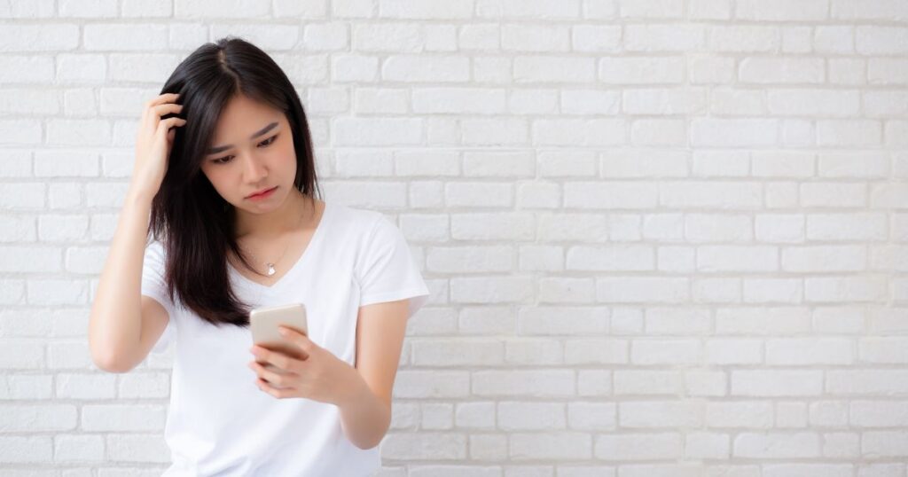 スマホの通知の内容に頭を抱え困ってしまう女性