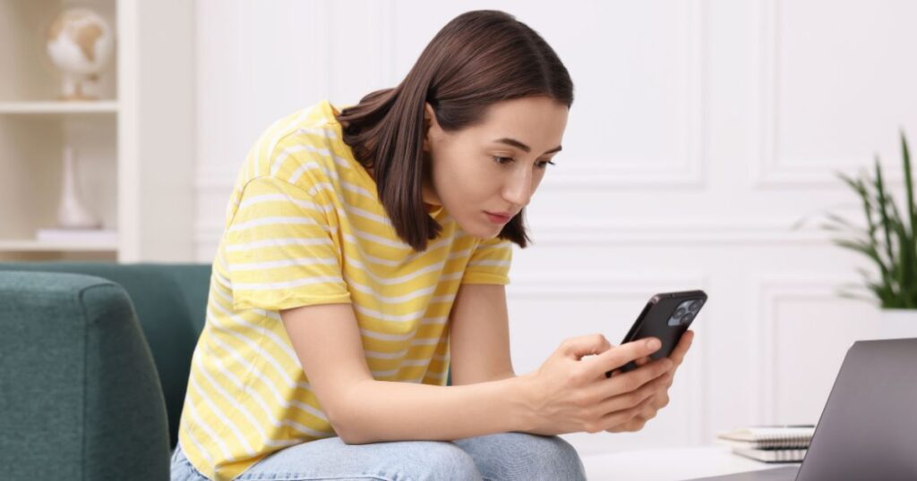 スマホの通知の内容に肩を落としてモヤモヤする女性