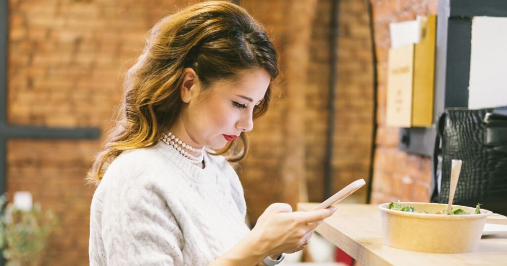 真剣な眼差しでスマートフォンを見つめる女性