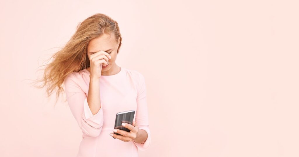 スマホのメッセージを読んで困った表情をする女性