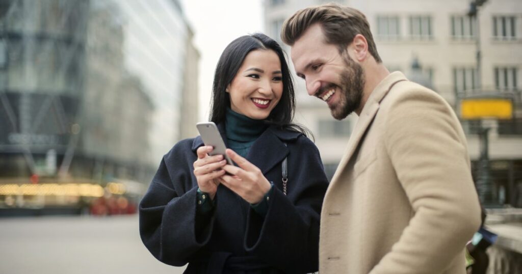 スマートフォンの画面を男性に見せる女性