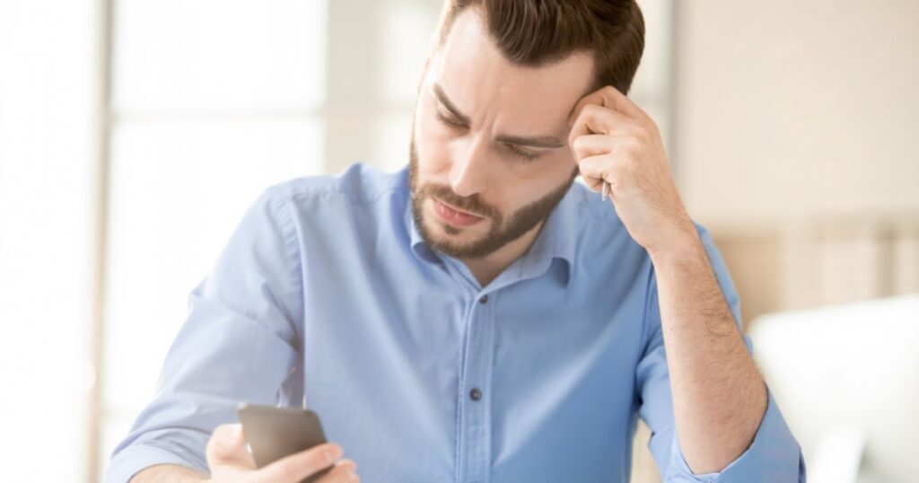 真剣な顔でスマートフォンを見つめる男性