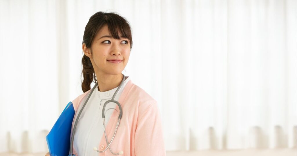聴診器を首にかけて微笑む看護師