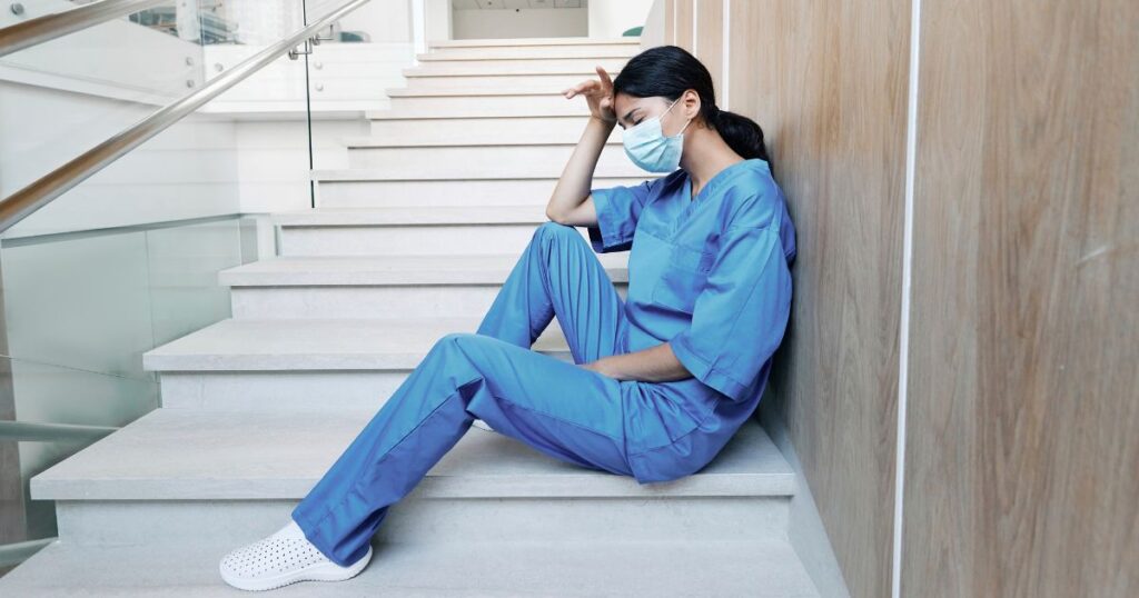 階段の途中で疲れ果てる看護師