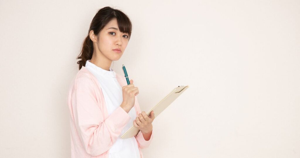カルテを持って考え込む看護師