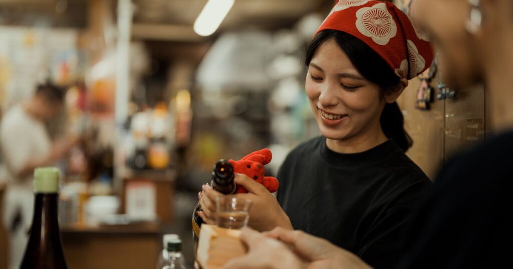 居酒屋でお酒を注ぐ女性店員