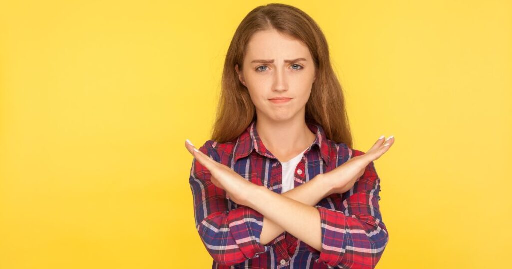 手でバツ印を作り拒絶する女性