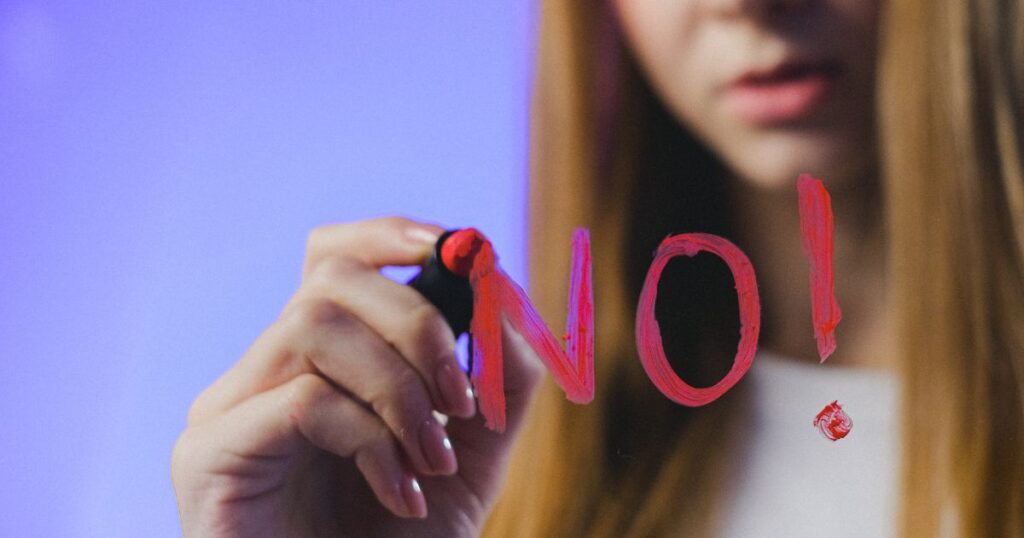口紅で鏡にNOという文字を書く女性