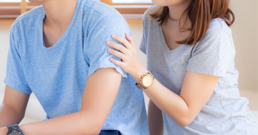 男性の肩に後ろから手を添える女性