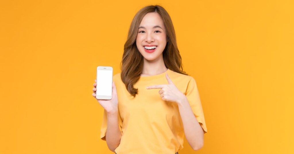 オレンジのシャツを着てスマホを指差す女性