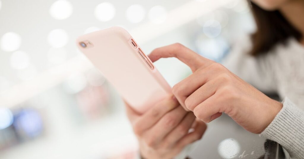 ピンクのスマホを操作する女性の指