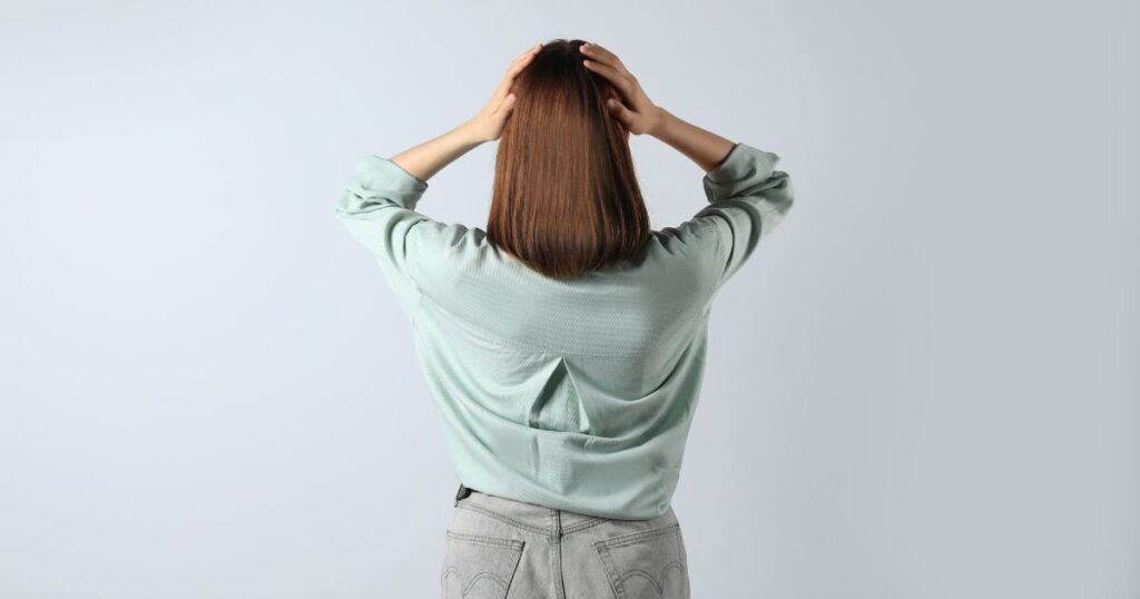 不安で頭を抱える女性の後ろ姿